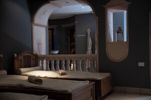 Un dormitorio con un espejo grande, una cama, cabecera de madera y un letrero que indica sauna.