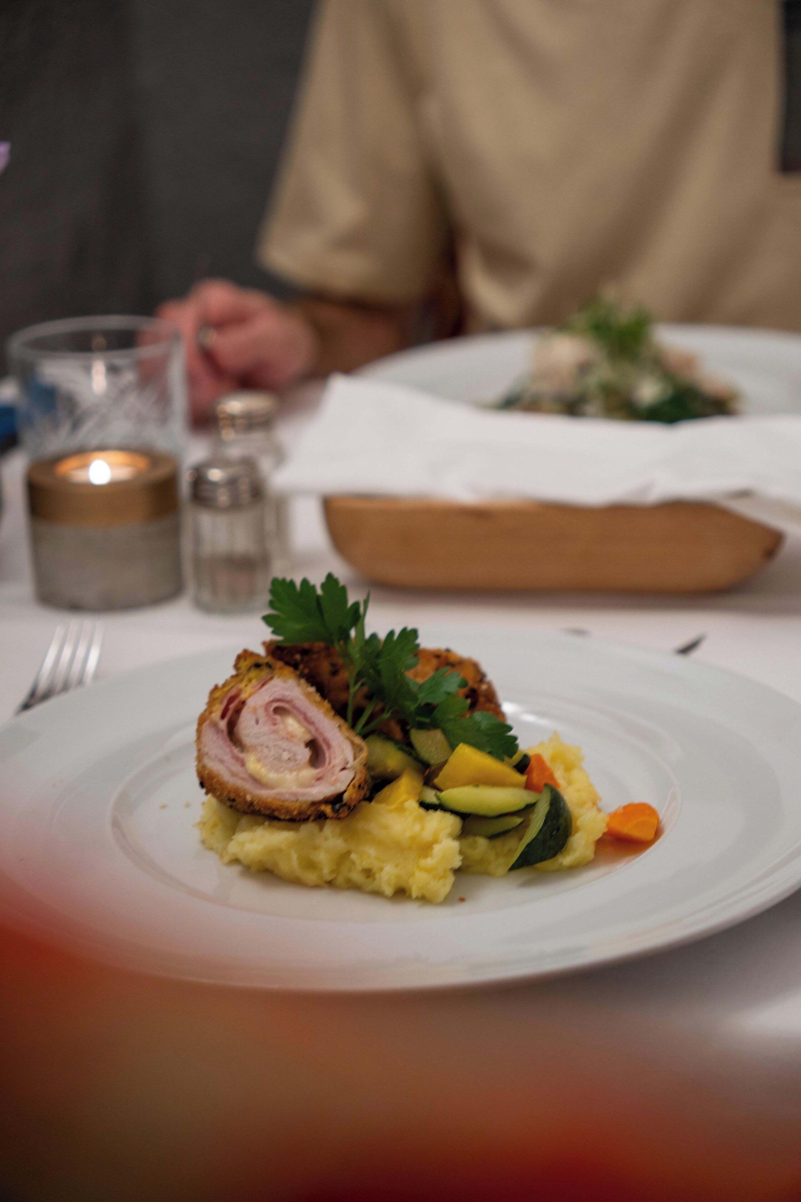 En tallerken med mad, bestående af en roulade, kartoffelmos og grøntsager.