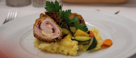A plate of food with a rolled meat dish, mashed potatoes, and vegetables.