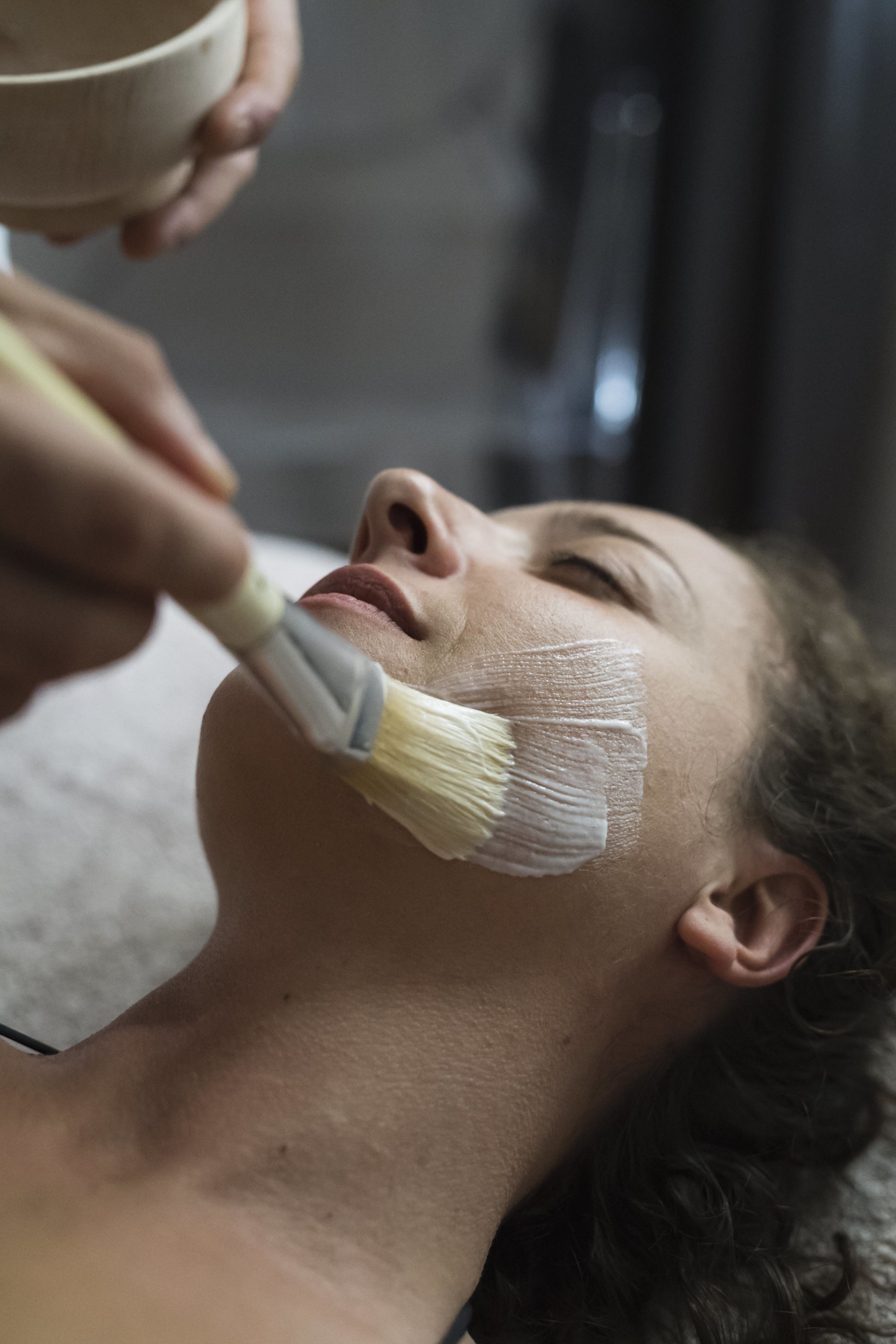 A person receiving a facial treatment with a brush.