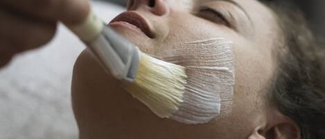 A person receiving a facial treatment with a brush.