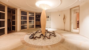 Una habitación circular con una lámpara central, armarios de madera y suelo de piedritas.