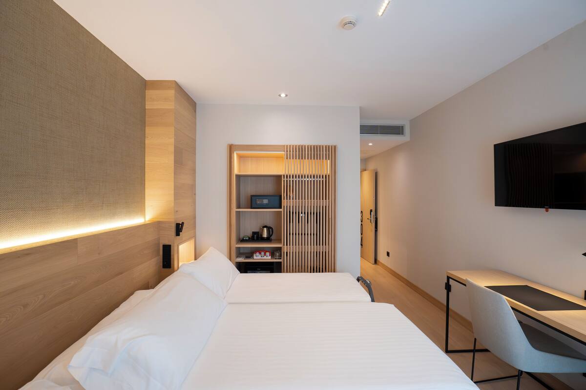 Une chambre d’hôtel moderne, dotée d’un grand lit, d’un bureau et d’une télévision.