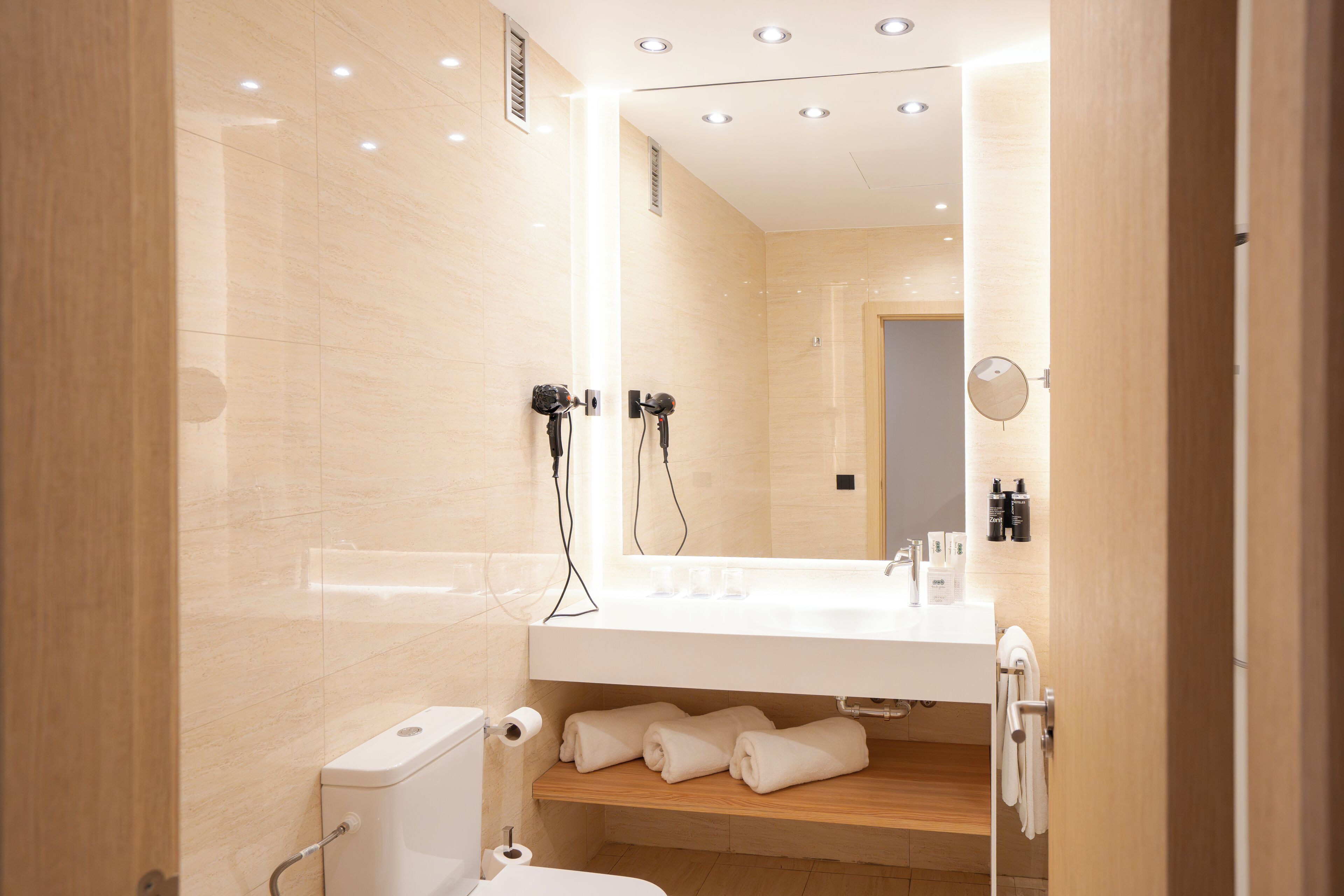 A modern bathroom with a white sink, mirror, and towel rack.