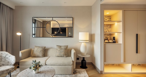A modern living room with a sofa, a round coffee table, a lamp, and a large mirror.