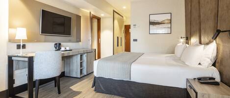 A hotel room with a bed, desk, chair, and a television.