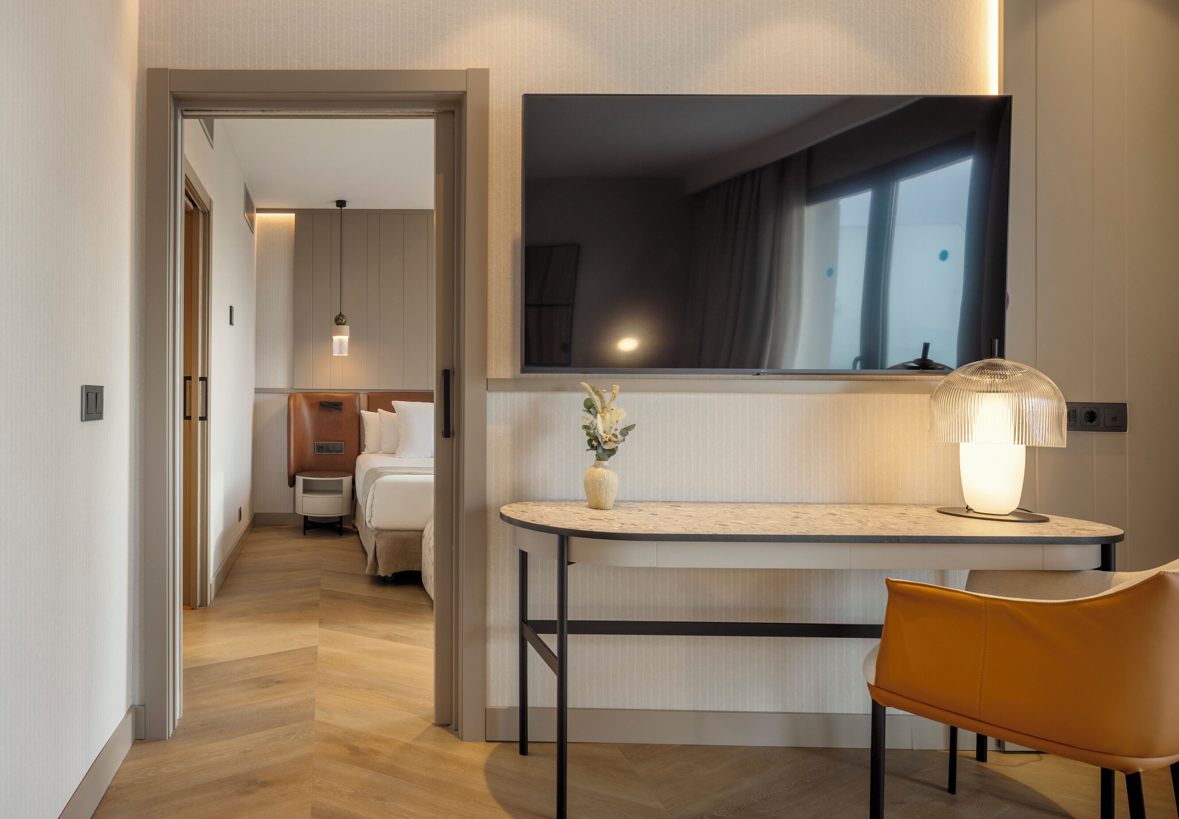 Una habitación de hotel con una cama, un escritorio con lámpara y un espejo.