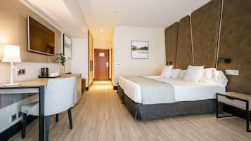 A hotel room with a bed, desk, chair, and a large mirror.