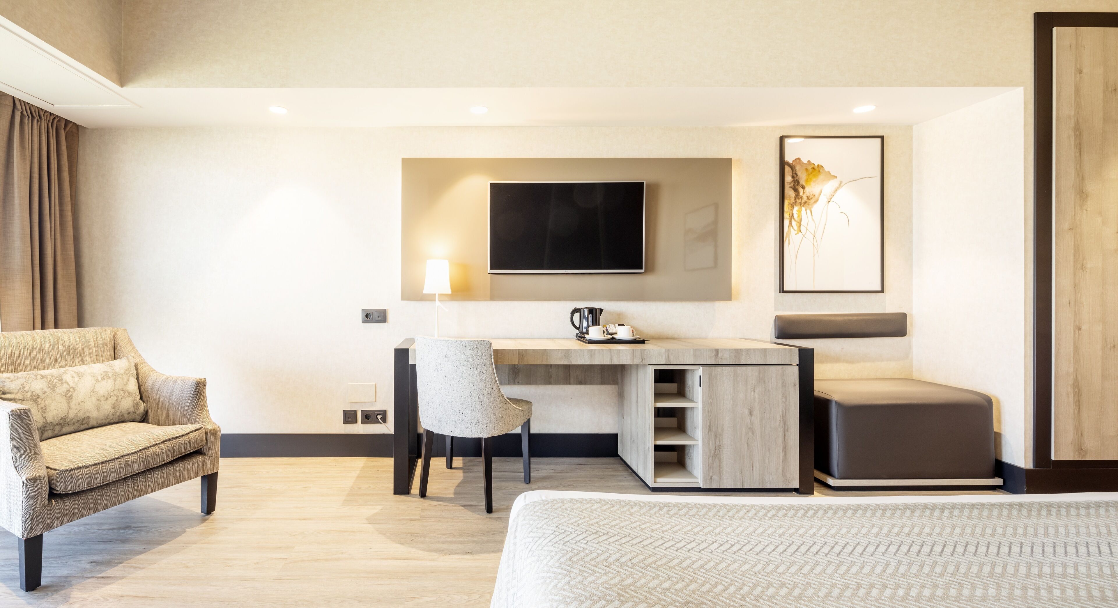 Una habitación de hotel moderna con una cama, un escritorio con silla, un televisor y un cuadro en la pared.