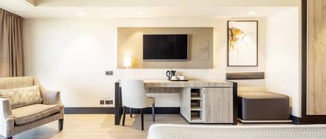Una habitación de hotel moderna con una cama, un escritorio con silla, un televisor y un cuadro en la pared.
