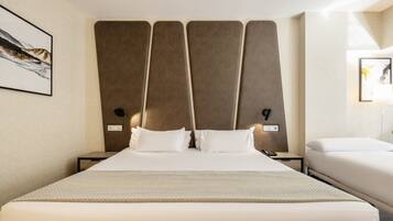 A hotel room with a large bed, two bedside tables, a nightstand, a lamp, and a framed picture on the wall.