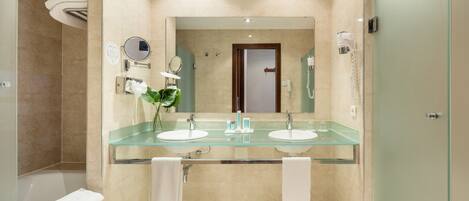 A modern bathroom with two sinks, a glass shower enclosure, and a large mirror.