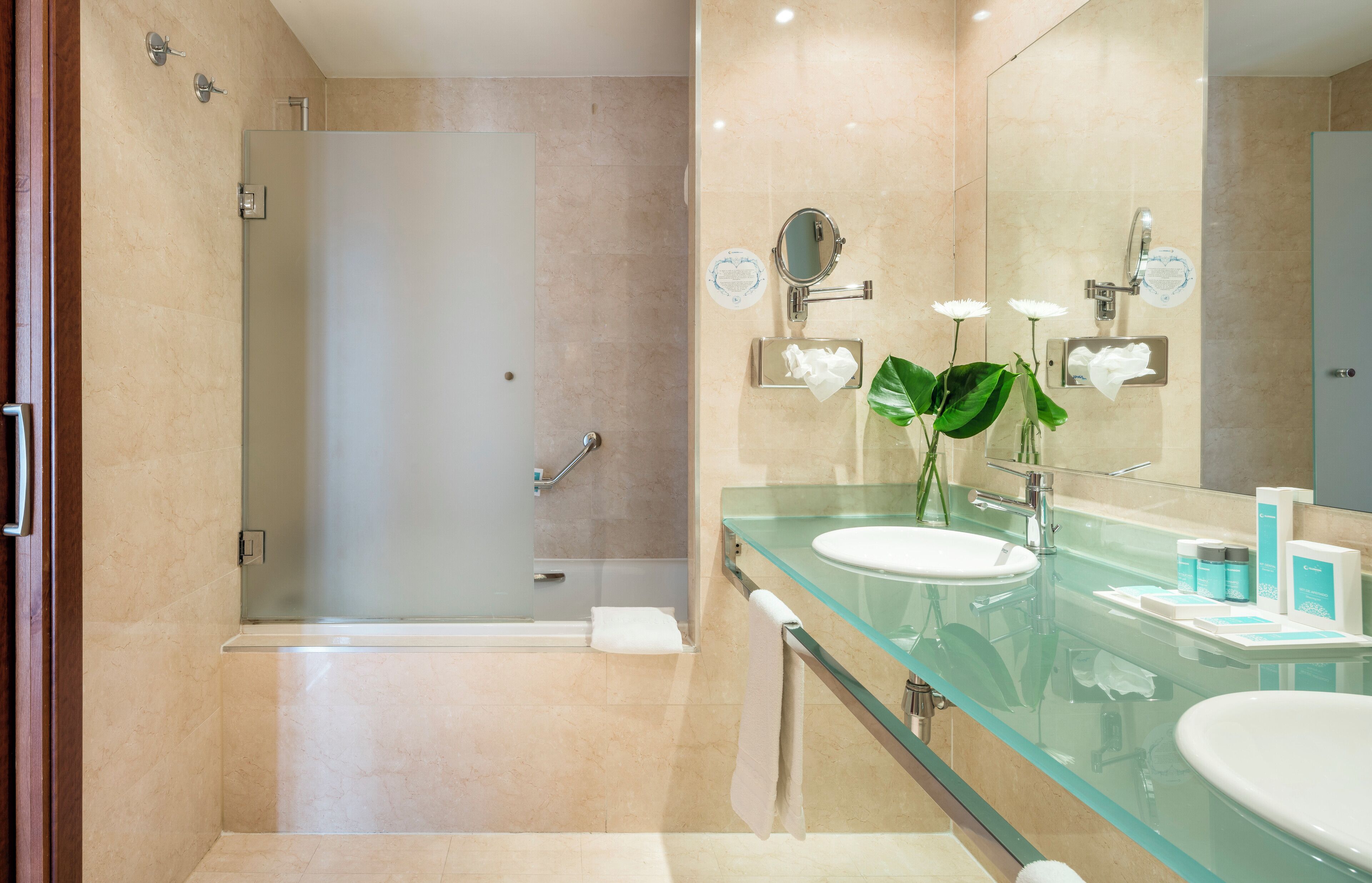 A modern bathroom with a glass shower enclosure, a glass vanity with a sink, and a large mirror.