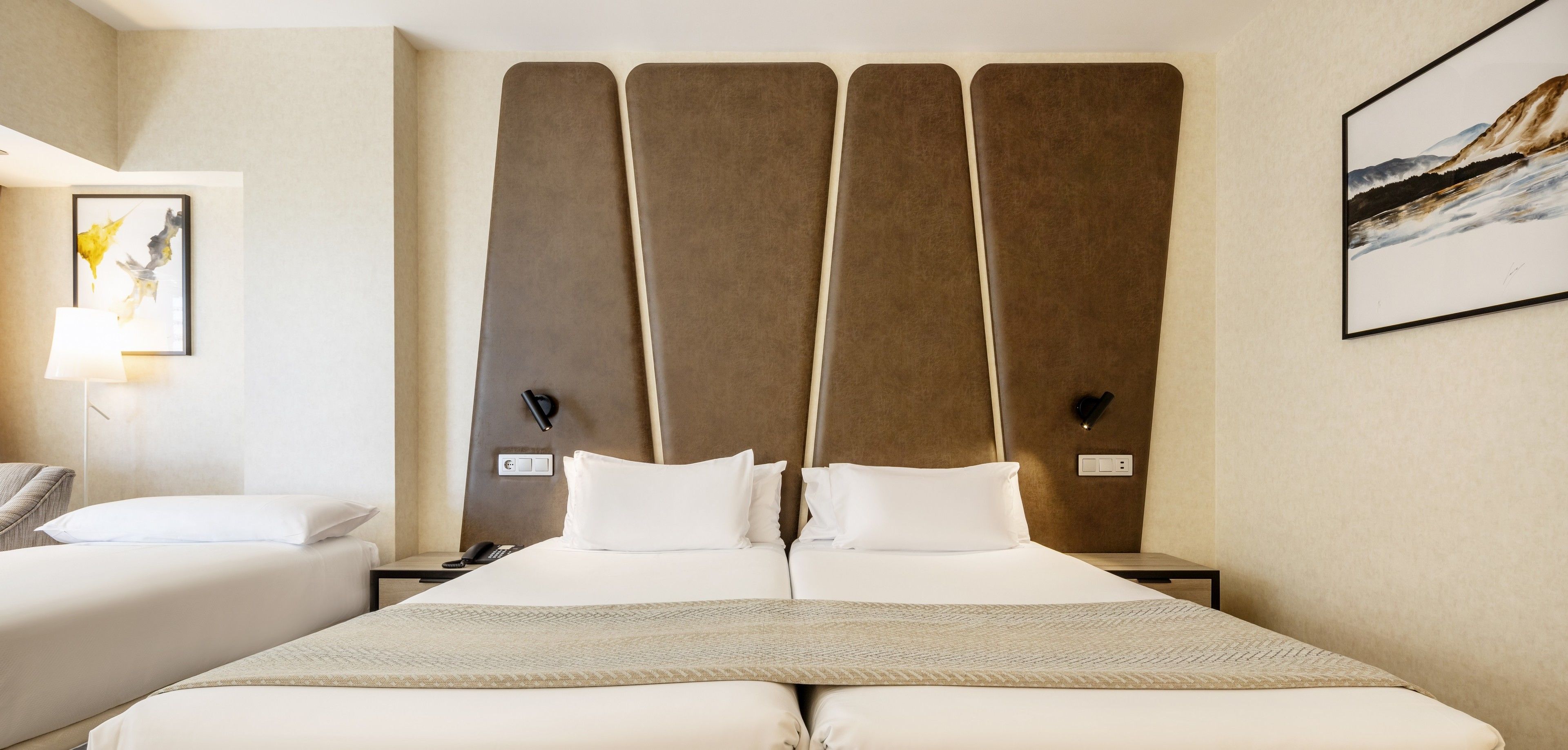 A hotel room with a large bed, two bedside tables, a lamp, and a painting on the wall.