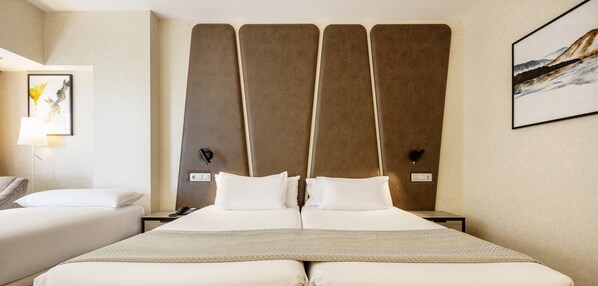 Una habitación de hotel con una cama grande, dos mesitas de noche, una lámpara y un cuadro en la pared.
