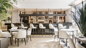 Zona de bar moderna con una barra larga, diferentes opciones de asientos y una variedad de botellas y copas.