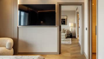 Una habitación de hotel moderna con televisión de pantalla plana, un sofá, una lámpara y suelo de madera.