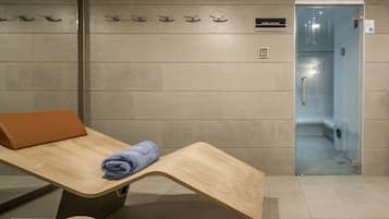 Un baño con un banco de madera, una toalla, una puerta de ducha de cristal y un letrero que dice "BAÑO TURCO".