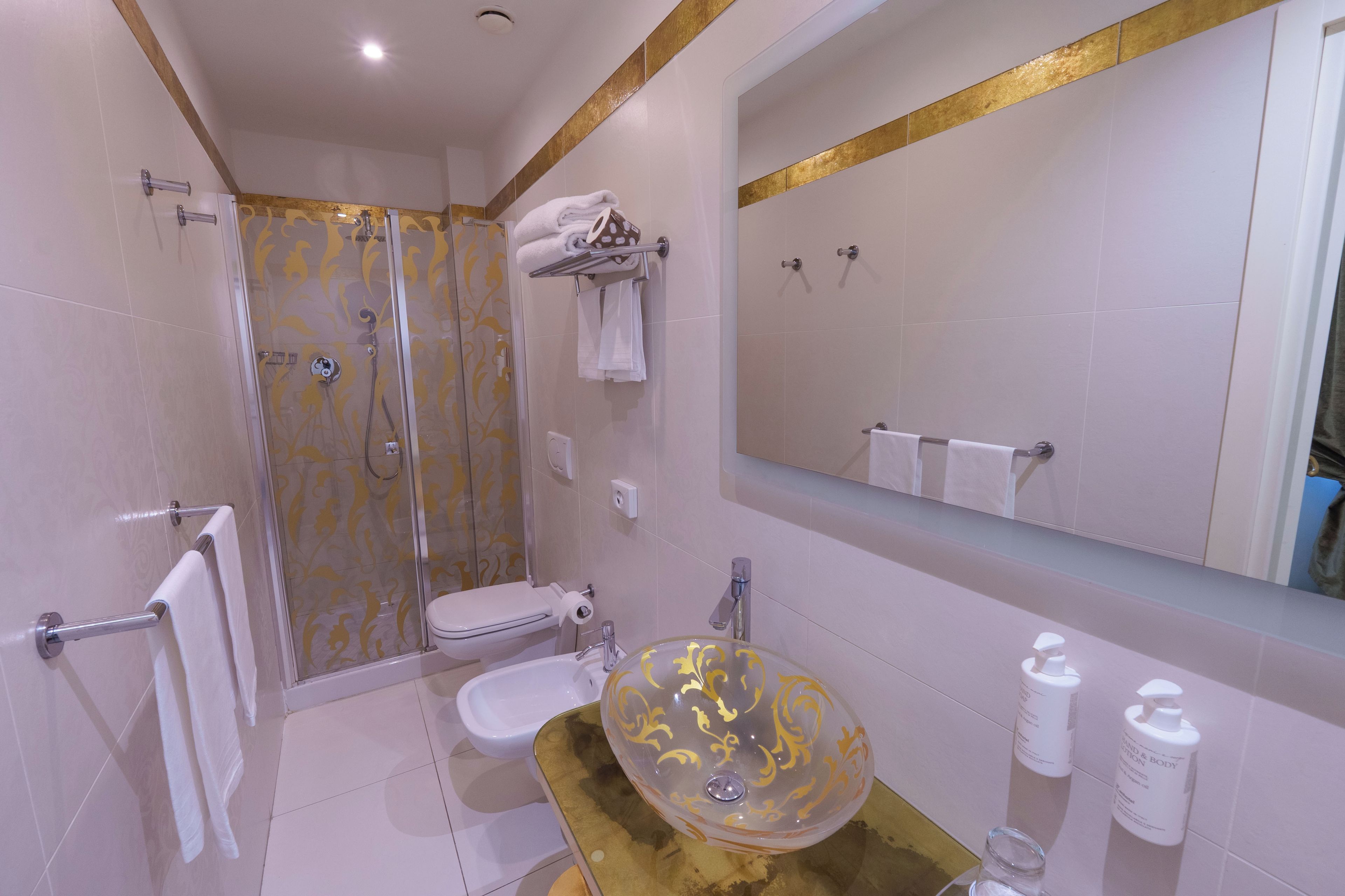 A modern bathroom with a glass bowl sink, a toilet, a shower with a glass door, and a large mirror.