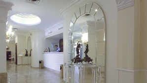 A lobby with a reception desk, a large arched mirror, and a statue on a pedestal. - Zanhotel Tre Vecchi (Bologna)