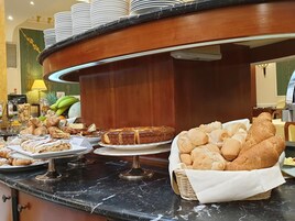 Noutopöydässä on tarjolla monenlaista ruokaa, kuten leivonnaisia, leipää ja kakku.