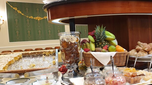Ein reichhaltiges Buffet mit verschiedenen Speisen, darunter Obst, Brot und ein Kuchen.