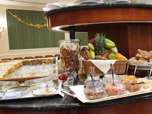Ein reichhaltiges Buffet mit verschiedenen Speisen, darunter Obst, Brot und ein Kuchen.
