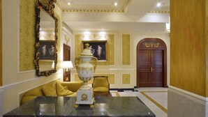 Ein luxuriöses Zimmer mit einem Marmortisch, einem großen, verzierten Spiegel und einer goldfarbenen Tür.