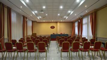 A conference room with rows of red chairs, a podium, and a sign indicating 'HOTEL EUROPA.'