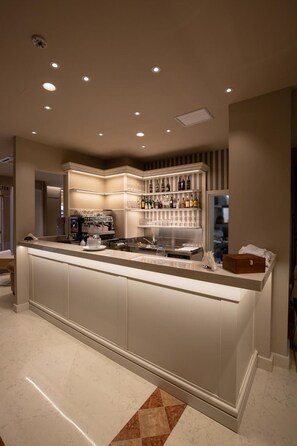 A bar area with a long counter, shelves with bottles, and a coffee machine. - Zanhotel Regina (Bologna)
