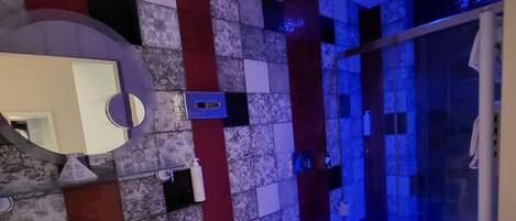 A modern bathroom with a large mirror, a sink, a bidet, and a shower area.