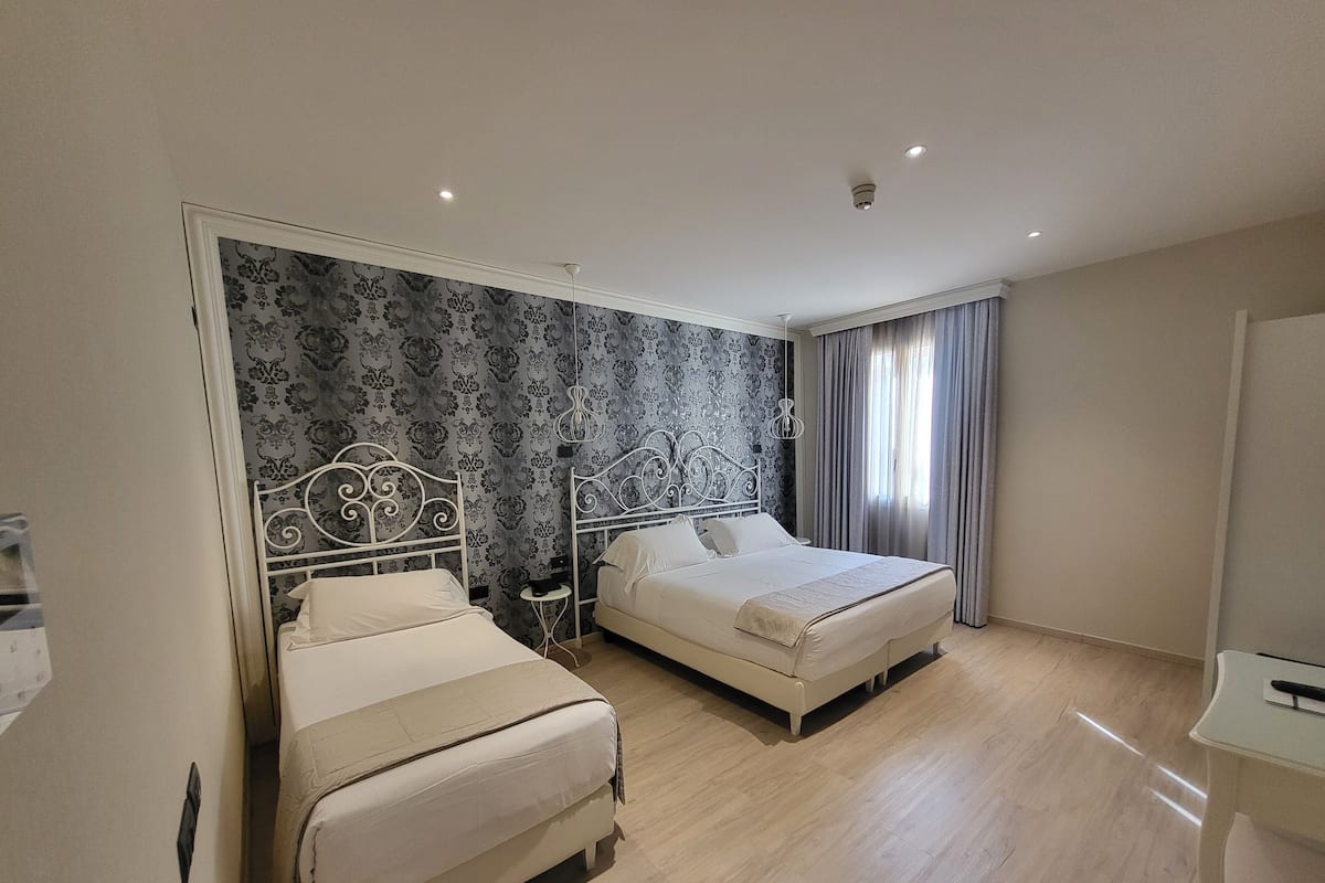 A hotel room with two beds, a small table, and a mirror.