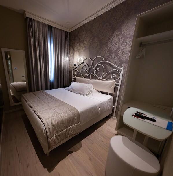 A hotel room with a bed, a bedside table, a mirror, and a bathroom area. - Zanhotel Regina (Bologna)