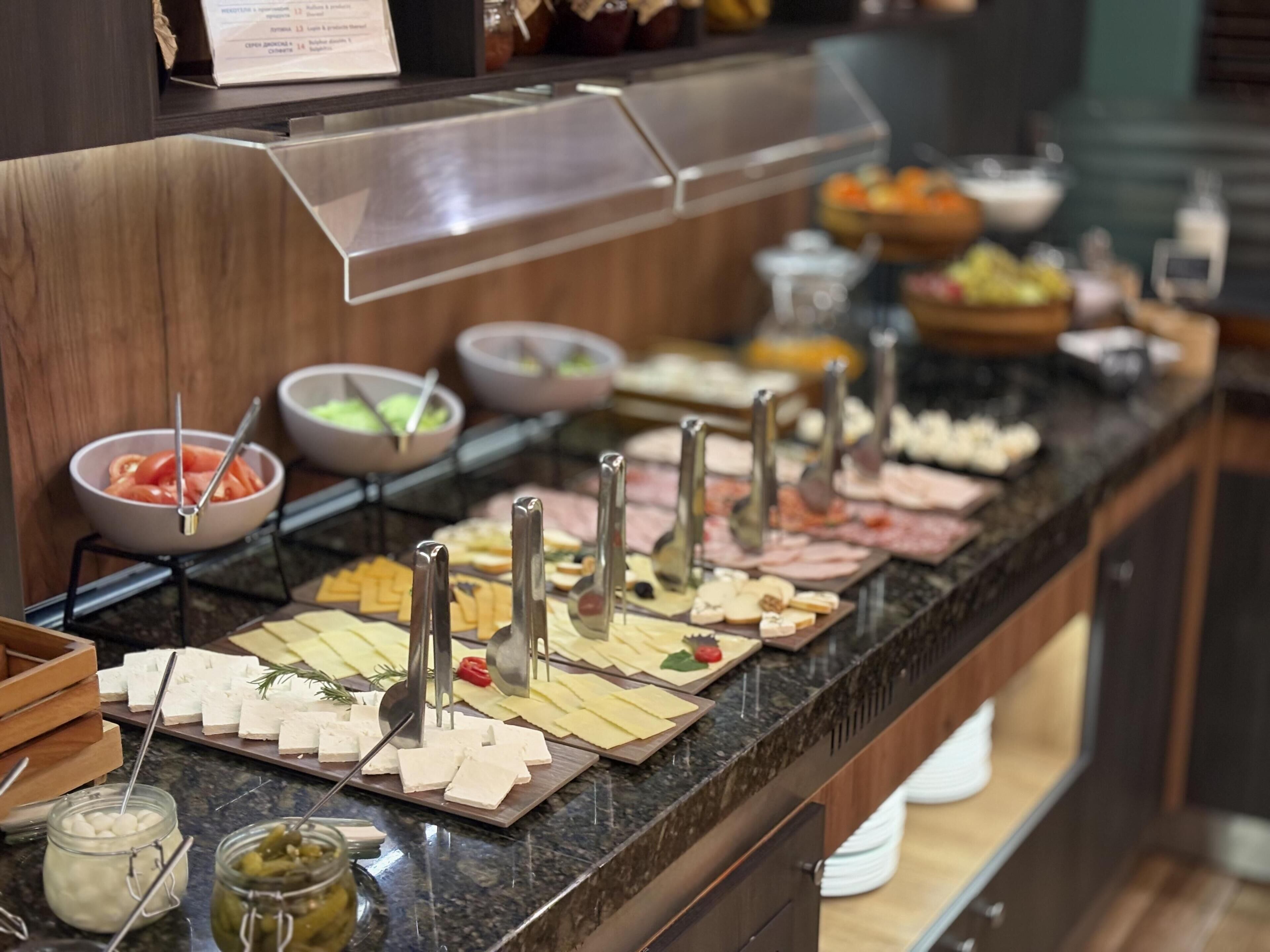 A buffet with various cheeses, meats, and condiments.