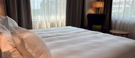 Una habitación de hotel con una cama grande, una silla, una mesita y una lámpara.