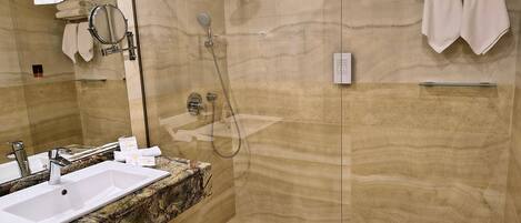 Un baño con lavamanos, espejo, ducha y toallero.