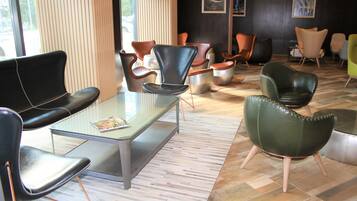 Un interior moderno con diversas opciones de asientos, incluyendo sillones de cuero y una mesa con superficie de vidrio.