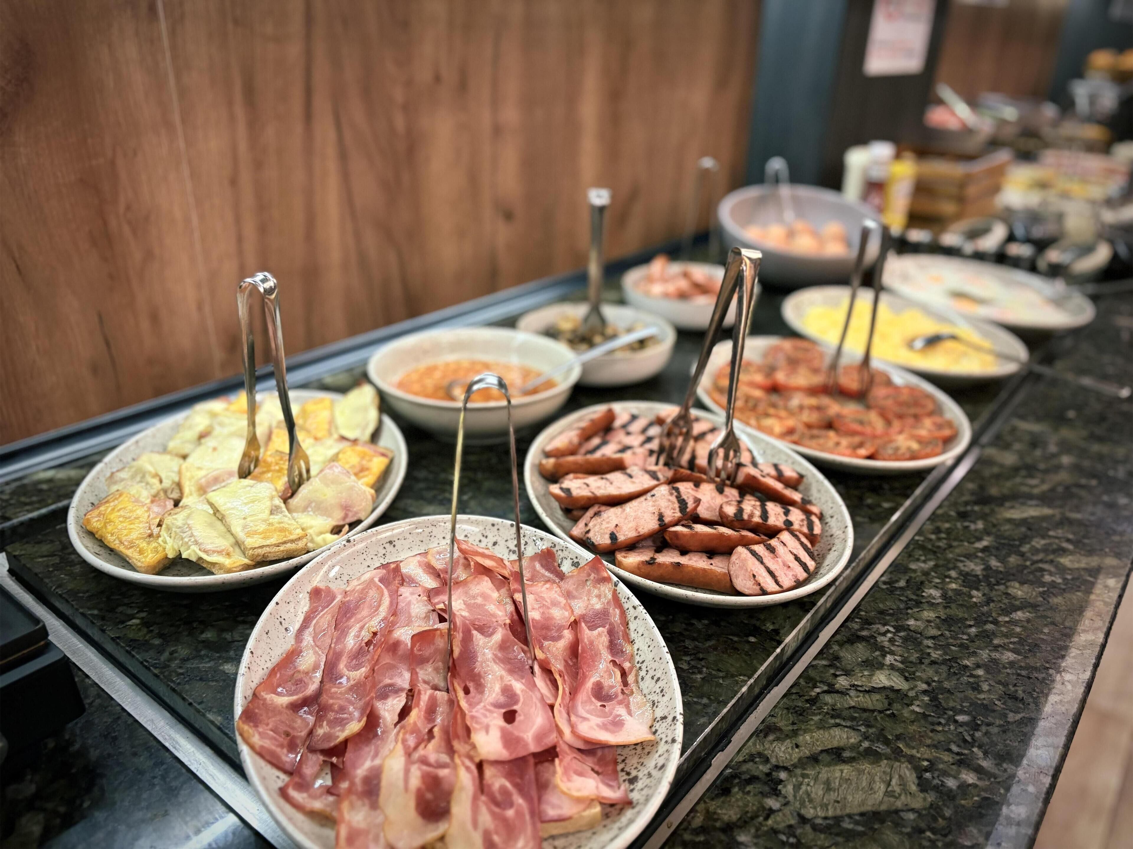 A buffet with various food items including pastries, meats, and sauces.