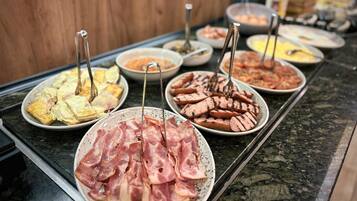 A buffet with various food items including pastries, meats, and sauces.