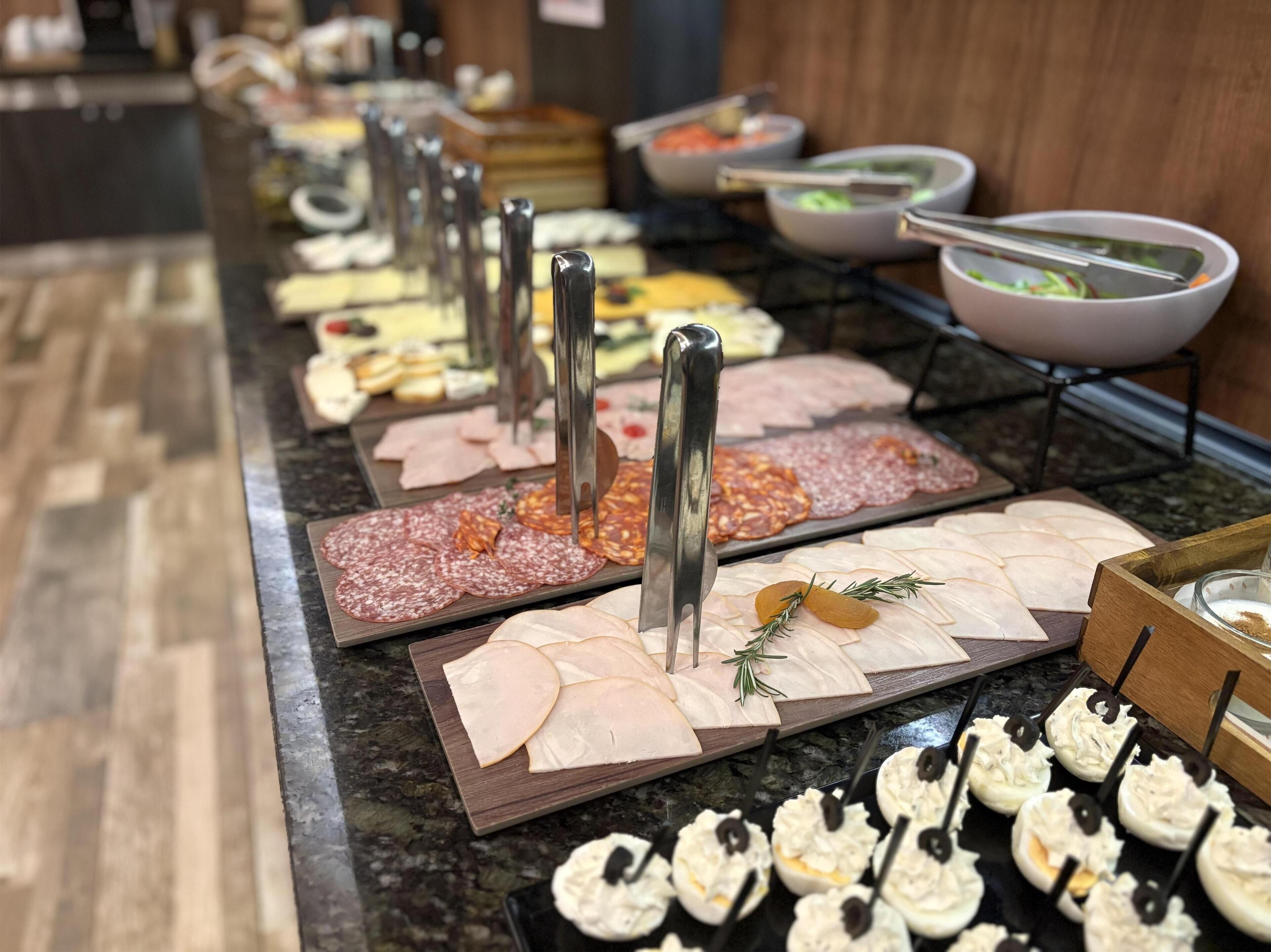 A buffet with various food items including meats, cheeses, and appetizers.