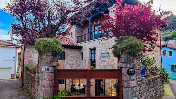 Un edificio de piedra con una reja de metal, plantas en macetas y un letrero que indica un restaurante.