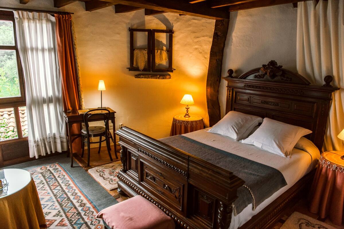 Une chambre confortable avec un lit en bois, deux lampes de chevet, une petite table et une chaise.