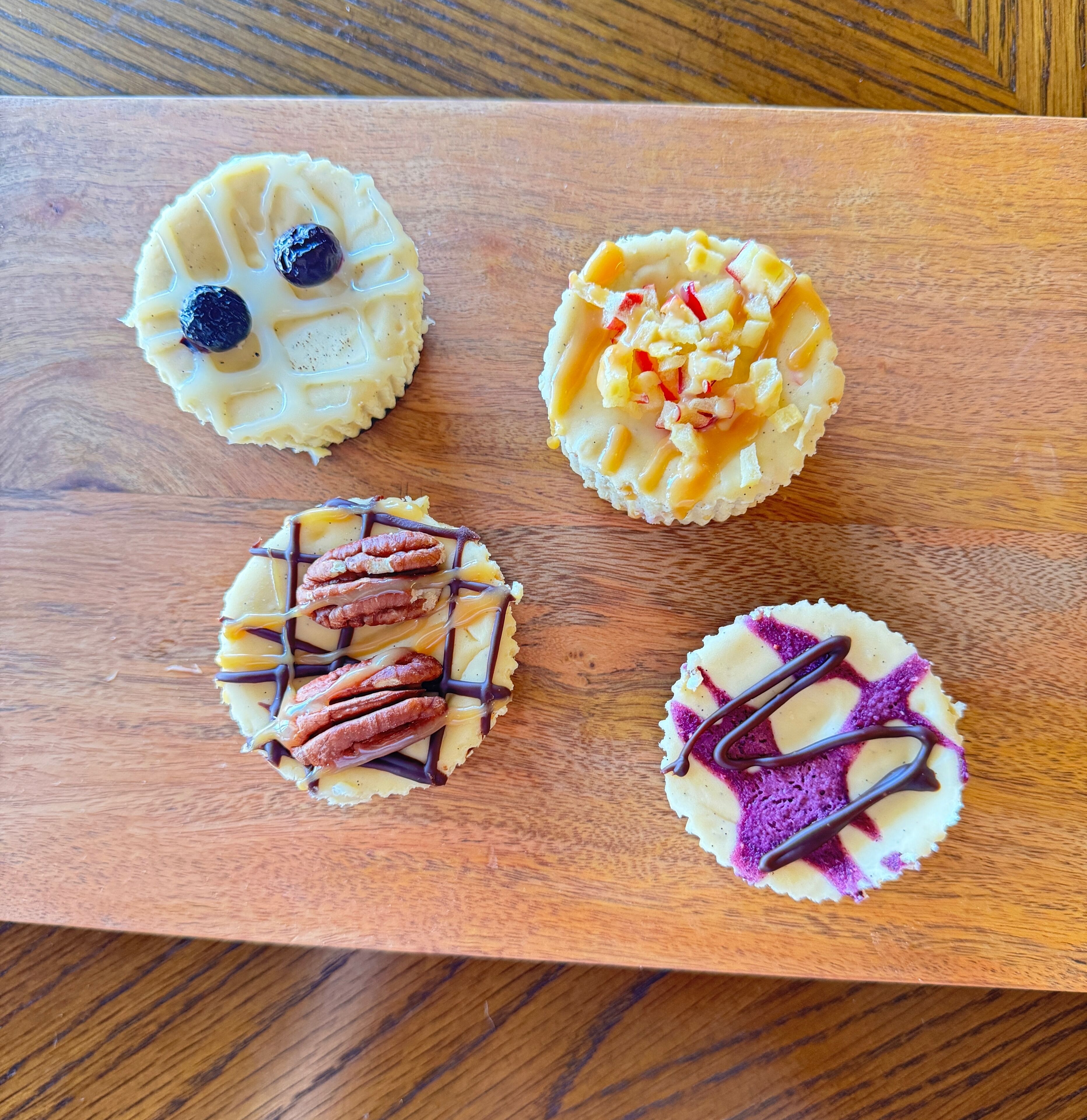 Four cupcakes on a wooden board.
