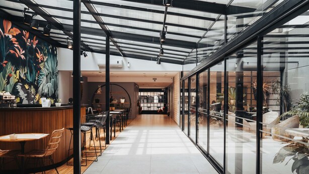 Un intérieur moderne avec un comptoir d’accueil en bois, un espace salon et de grandes fenêtres.