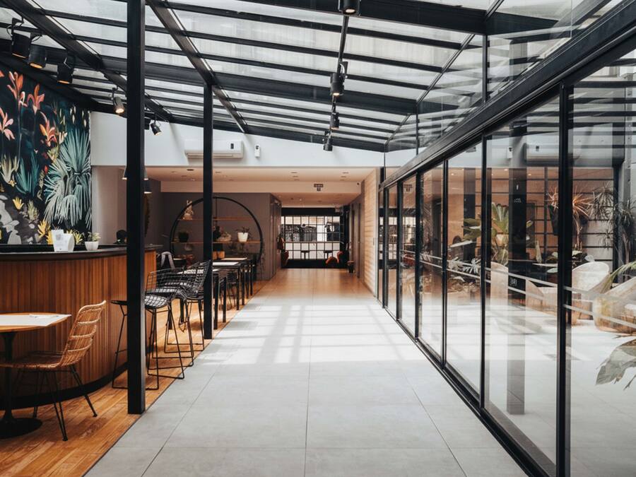 Un interior moderno con una recepción de madera, zona de estar y ventanas amplias.