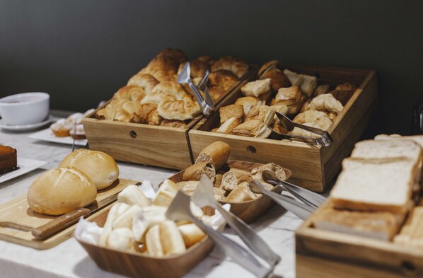A buffet with various baked goods and utensils.