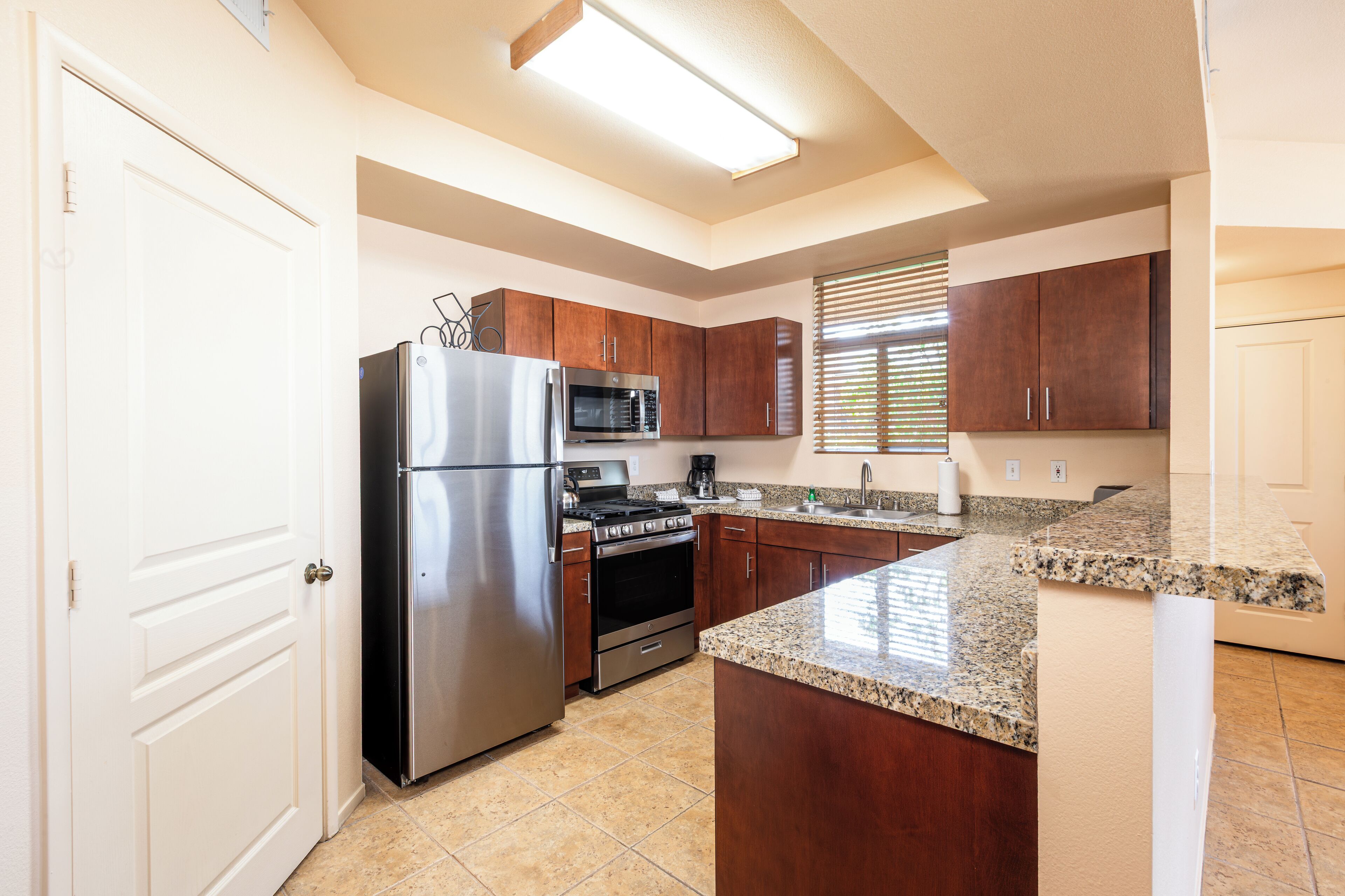 A kitchen with stainless steel appliances, wooden cabinets, and a granite countertop.