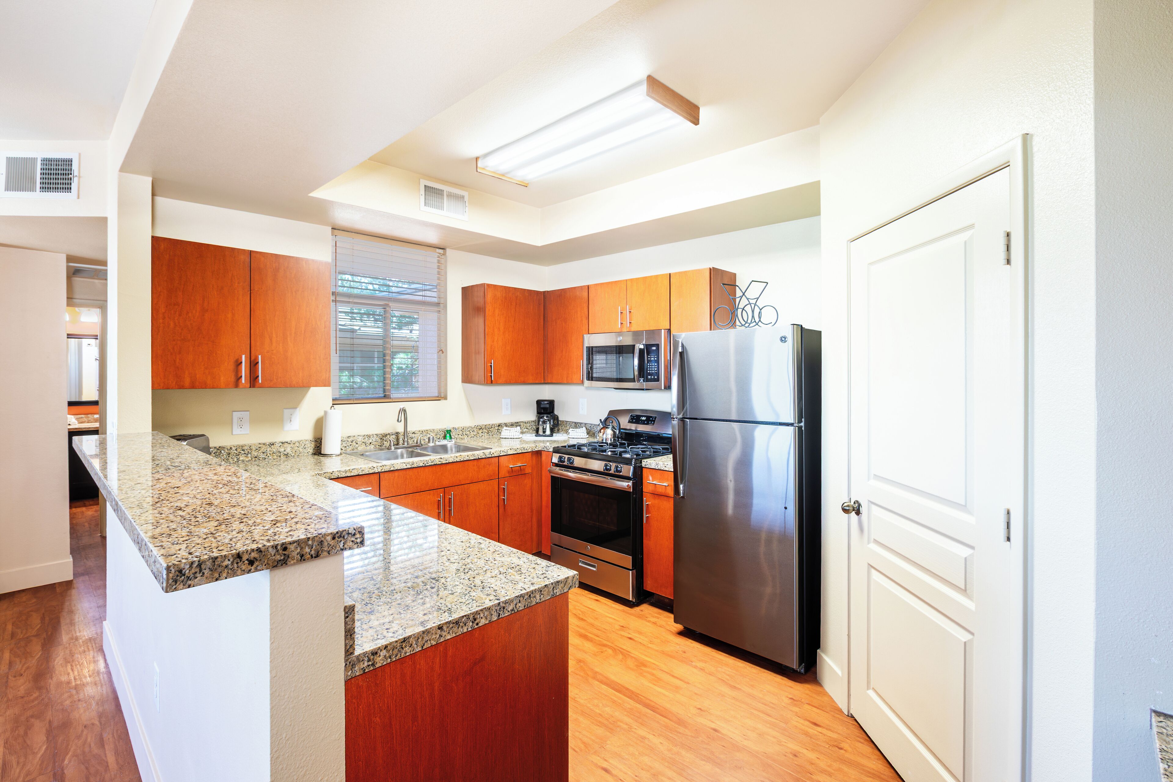 A modern kitchen with granite countertops, stainless steel appliances, and wooden cabinets.