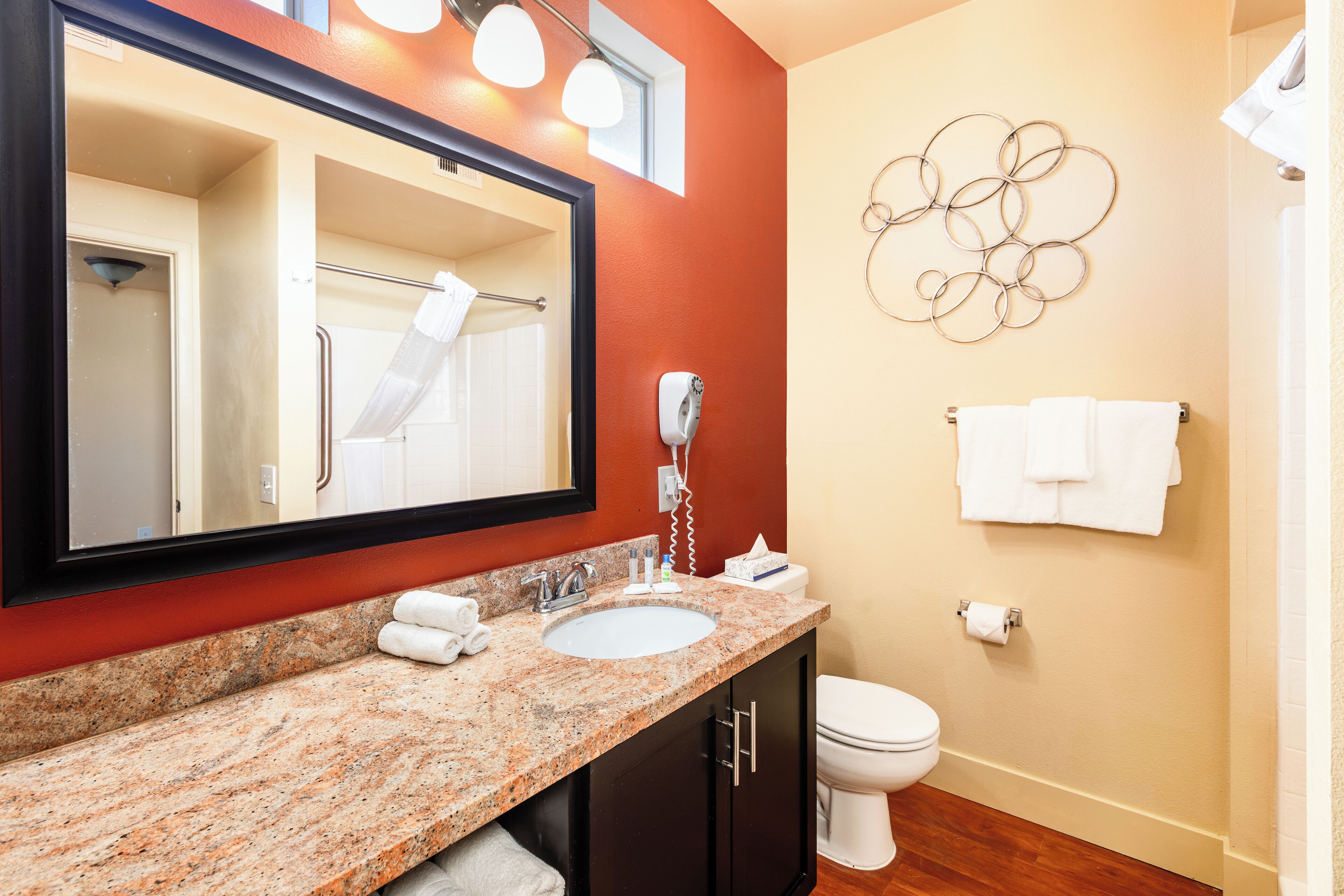 Une salle de bain avec un lavabo à vasque en granit, un miroir, des toilettes et un porte-serviettes.
