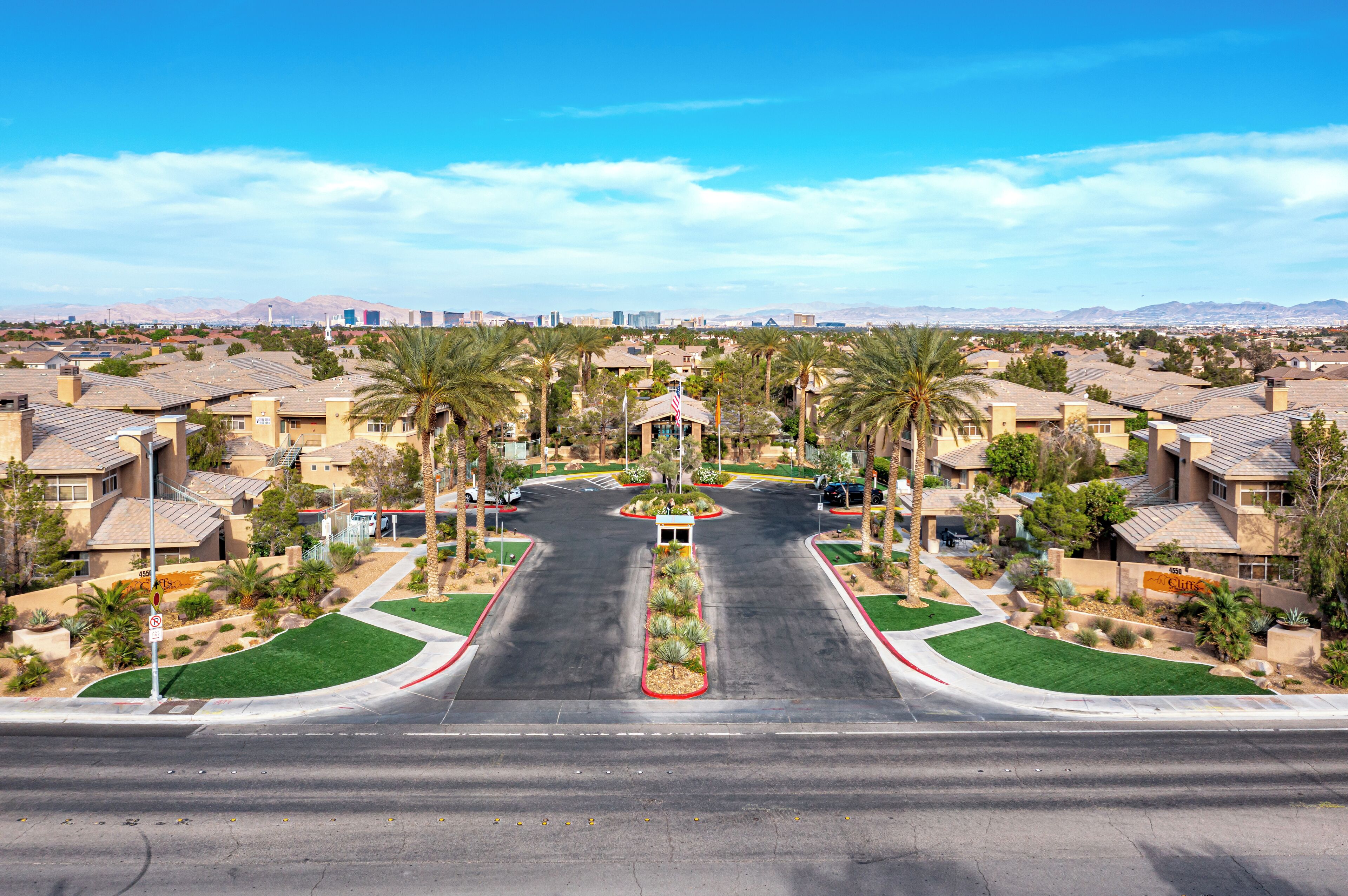 A residential street with houses, palm trees, and a central road.